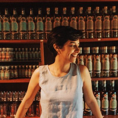 Duda Porto diante da estante de garrafas da Engenhoca